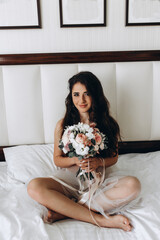 Morning of the bride. Girl in white lingerie. Bridal bouquet. Bedroom.