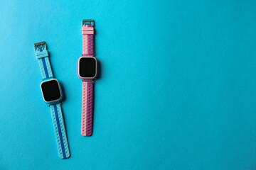 Obraz premium Kid smart watches on light blue background, flat lay. Space for text