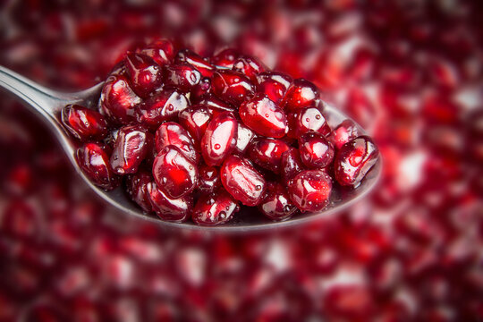 A tablespoon with pomegranate berries. Delicious berries.