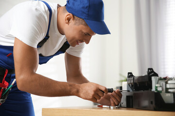 Repairman with screwdriver fixing modern printer in office