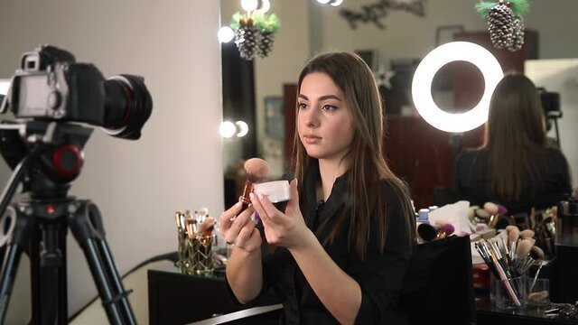 Profession make up artist woman reviewing beauty products on a video blog at beauty studio. Woman use ring lamp