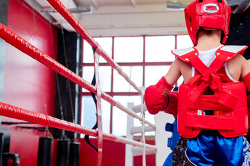 boxer in the ring. Boxer in full gear. Children's sports. Thai boxing. Boxing competition. Hand protection.