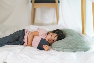 Asian cute little girl watching cartoon in smartphone while lying in a blanket fort in living room at home for perfect hideout away from their other family members and for them to play imaginatively.