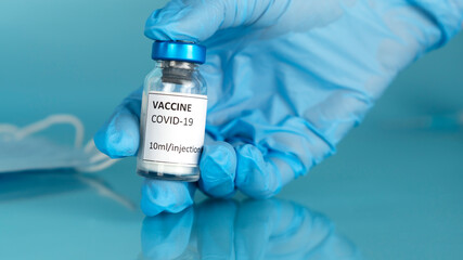 Coronavirus vaccine vial. The doctor's gloved hand holds vaccine ampoule for Covid-19 vaccination. Stop Covid. Take off face mask.