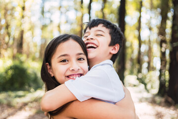 Fototapeta premium Portrait of two little brothers hugging each other tightly while playing outdoors.