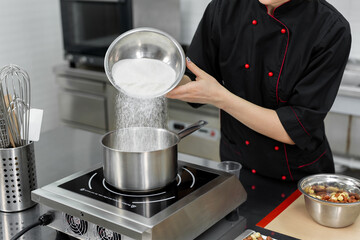 Pastry chef pours the sugar into a saucepan.