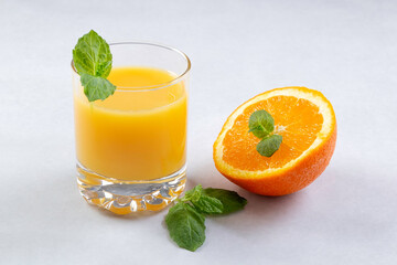 Fresh oranges and orange juice in glasses on an orange background. Mint leaves. Still life. Close up. Copy space.
