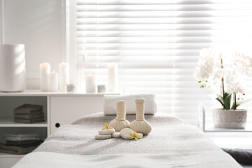 Herbal bags, orchid flowers and stones on couch in spa salon