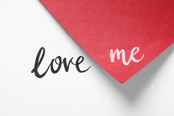 Phrase Love Me written on white and red paper
