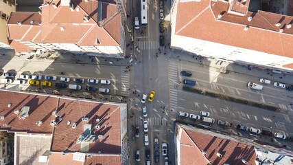 Aerial view of the city traffics at the center. Vehicles are moving on the road between buildings.