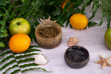 image of homemade cosmetics ingredients. aroma theme. Black mask, clay. organic cosmetics with extracts of herbs apples, lemons and oranges on white leaf green background
