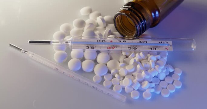 Fever Thermometer on top of white Pills and Medicine. Diagnostic and Cure for Illness and Sickness