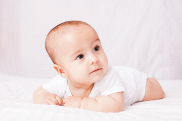 Adorable baby lying on the stomach at the white