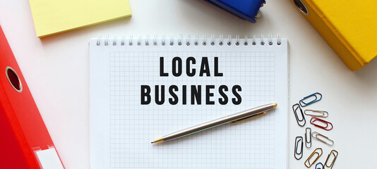 Notepad with text LOCAL BUSINESS on a white background, near document folder and office supplies.