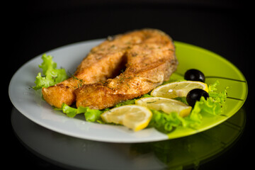 piece of fried salmon fish in a plate with lemon
