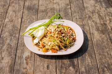 Papaya salad with pink plates placed on a wooden table.