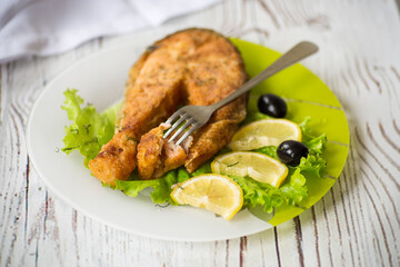 piece of fried salmon fish in a plate with lemon