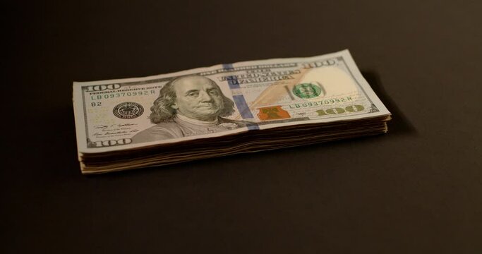 Stack of Dollars on dark Background, 100 Dollar Bills piled on each other.