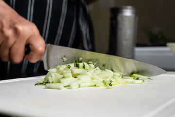 Chef with sharp knife chopping zucchini squash.