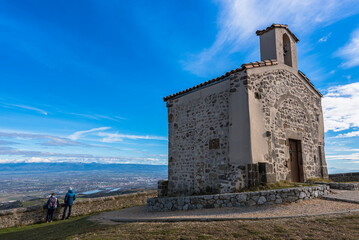 Tourists enjoying the breathtaking view on the Rhone valley and Valence city from high lookout of the belvèdere du pic of the french Saint-Romain-de-Lerps village with the tiny chapel behind. - obrazy, fototapety, plakaty