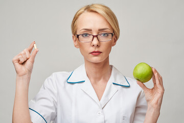 nutritionist doctor healthy lifestyle concept - holding organic fresh green apple and vitamin...