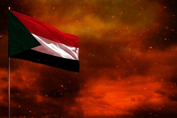 Fluttering Sudan flag mockup with blank space for your text on crimson red sky with smoke pillars...