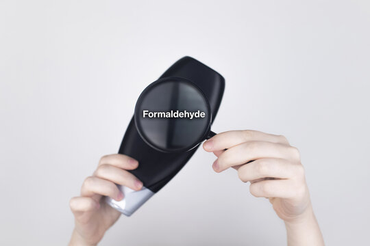 Chemical components on the shampoo label: Formaldehyde. Female hands hold a magnifying glass on the jar, which indicates the harmful ingredient. White background, place for your text