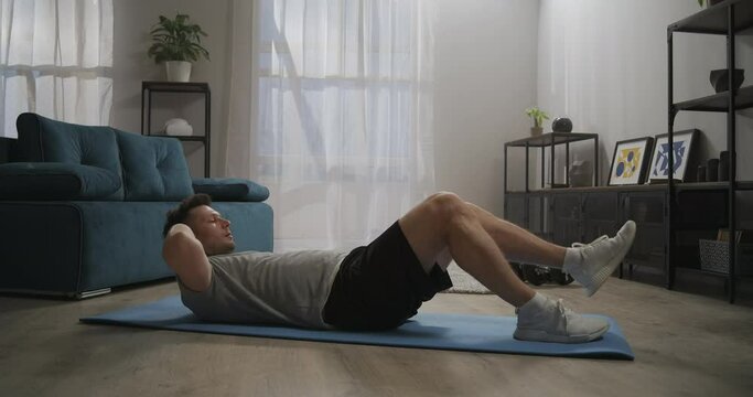 workout at home, man is lying on floor, lifting torso and legs, exercise for healthy and beautiful body