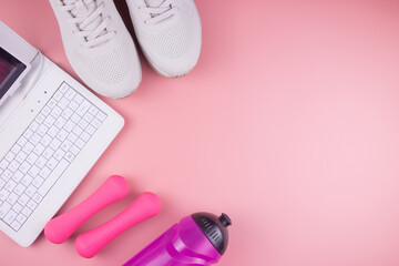 Online fitness. Sneakers, laptop, fitness bracelet, water bottle and dumbbells, on a pink background, workout online.