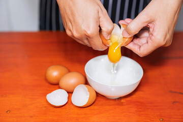 breaks egg in ceramic white bowl