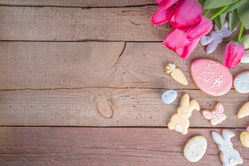 Easter gingerbread cookies, spring flowers and eggs on wooden background. Cozy home Easter greeeting card concept, copy space top view