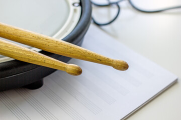 Drum sticks made of wood and a pad from an electronic drum kit close-up. Music hobby concept. Home art hobbies authentic concept. Musical hobby drums