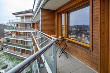 Wooden table and chairs on balcony in modern luxury apartment complex. View of winter city with...