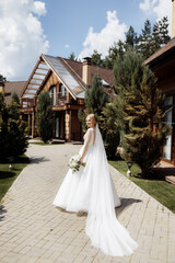 Fototapeta premium bride in a dress standing in a green garden and holding a wedding bouquet of flowers and greenery