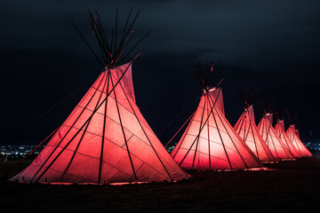 Red, glowing native american teepees at night
