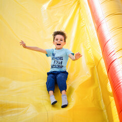 Smiling little boy playing on inflatable slide