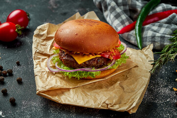 Juicy and appetizing burger with beef, lettuce, cheese and tomatoes on a vintage plate on a wooden...