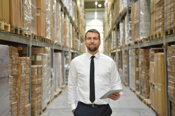 portrait friendly businessman/ manager in suit working in the warehouse of a company - control of inventories