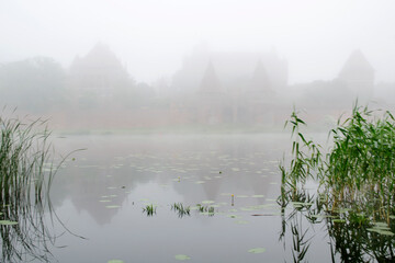 Zamek w Malborku i jego odbicie w rzece Nogat, mglisty poranek