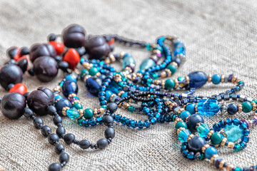 Various types of beads and necklaces on gray canvas fabric