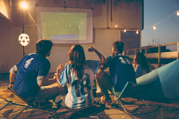 Friends watching football on a building rooftop terrace