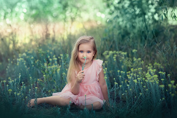 a girl in a pink dress sits on the grass on a summer day