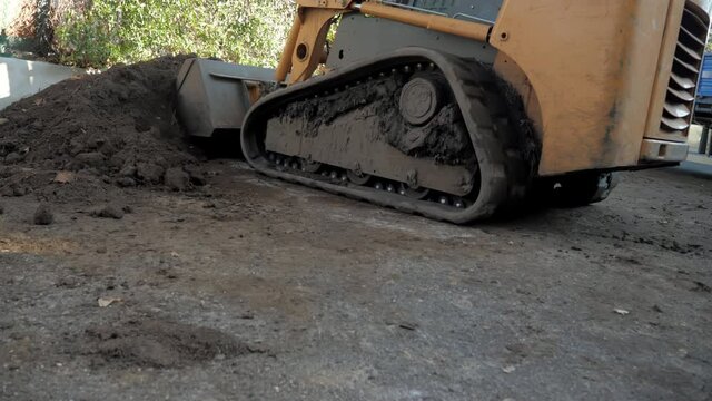 The tractor loader is picking up soil with its large bucket