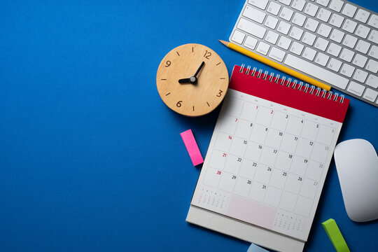 close up of calendar, alarm clock and accessories on the blue table background, planning for business meeting or travel planning concept