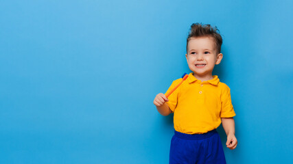 Happy child kid boy brushing teeth with toothbrush on blue background. Health care, dental hygiene. Mockup, copy space