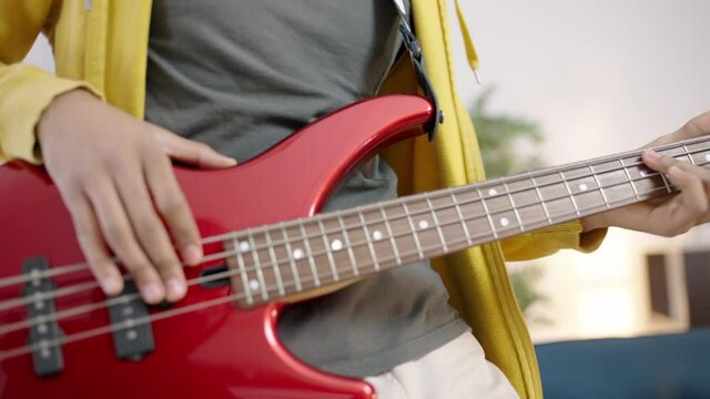 Energetic teen guy playing electric guitar like a rock star, slow-motion