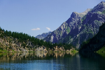 mountain lake with nice reflection and high rocky mountains in the background