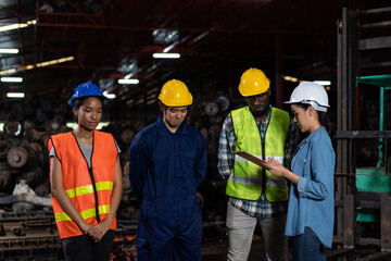 Group of diversity factory worker discussing about work, project, target or complain at old garage parts storage warehouse. Group of factory worker meeting and wearing safety vest and helmet