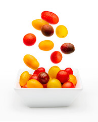 Colorful cherry tomatoes (red, garnet and yellow), fresh and raw falling into a bold. With water drops Isolated on white background