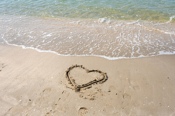 blurred of drawing heart on a yellow sand at a beautiful seascape background. Horizontal composition.